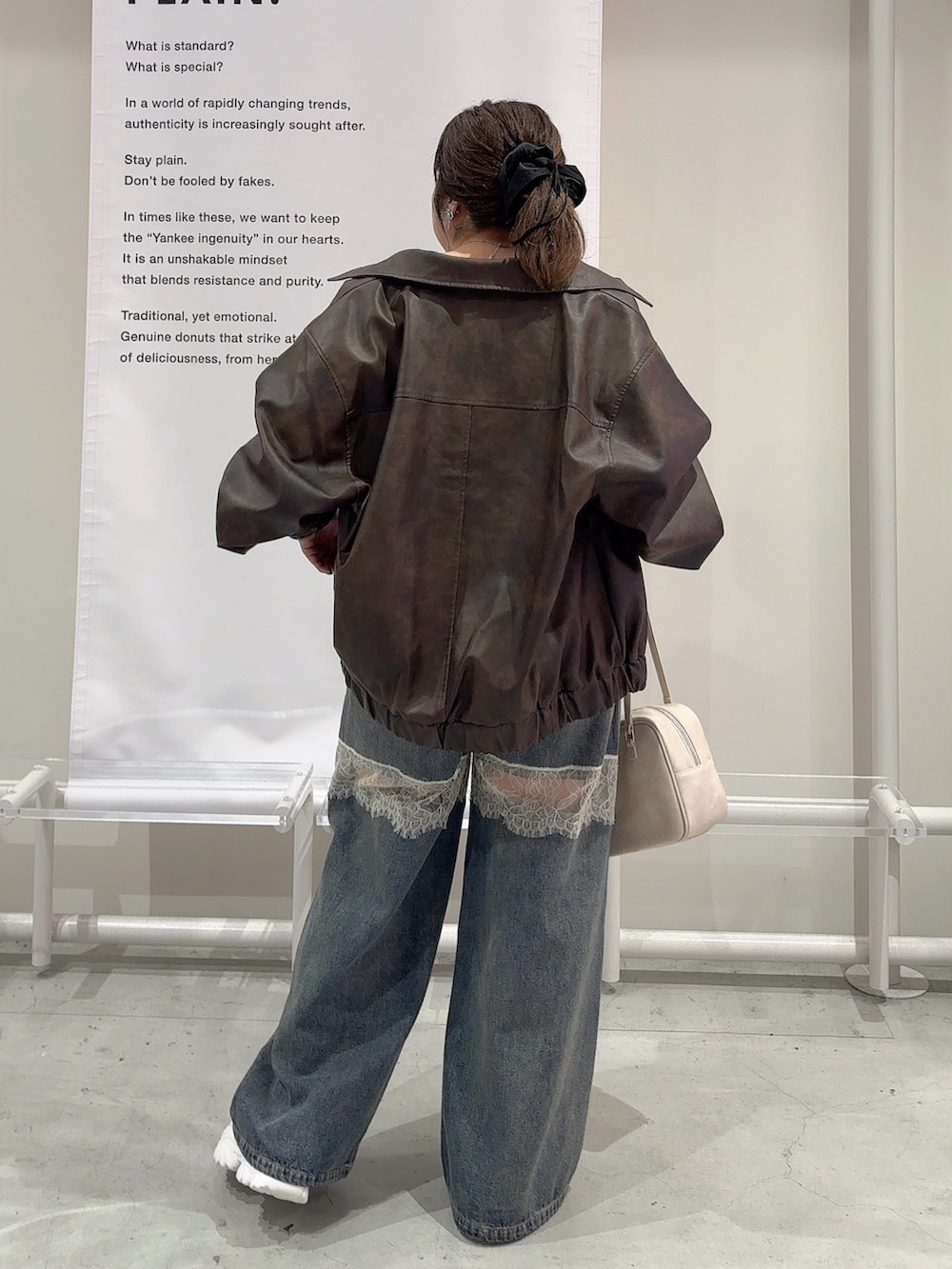 ブラウン系のブルゾン、ホワイト系のTシャツ/カットソー、ブルー系のデニムパンツを着用したレディースの秋コーディネートの3枚目の写真