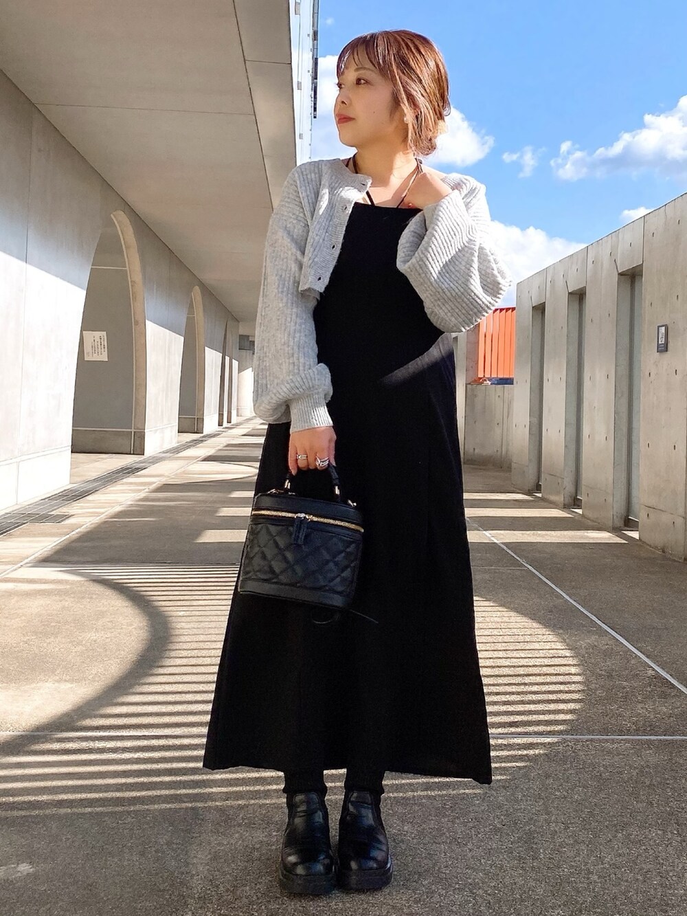 ブラック系のワンピース、ブラック系のショルダーバッグ、ブラック系のブーツを着用したレディースの冬コーディネートの2枚目の写真