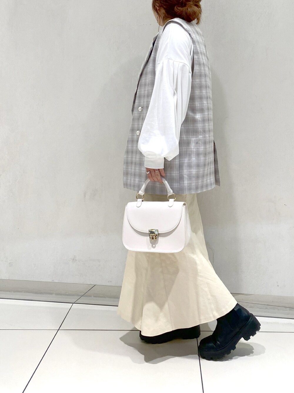 ホワイト系のスカート、ブラック系のブーツ、ホワイト系のショルダーバッグを着用したレディースの冬コーディネートの2枚目の写真
