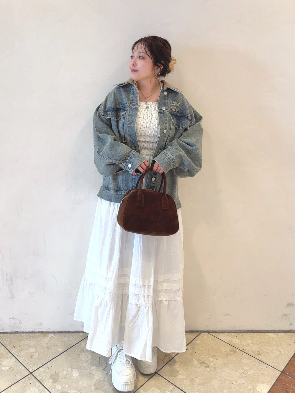 ブルー系のデニムジャケット、ホワイト系のTシャツ/カットソー、ブラウン系のショルダーバッグを着用したレディースの冬コーディネートの2枚目の写真