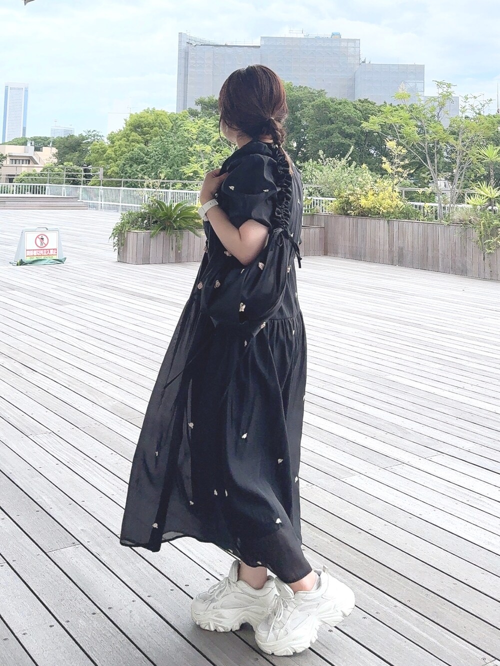 ブラック系のワンピース、ブラック系のショルダーバッグ、ホワイト系のスニーカーを着用したレディースの夏コーディネートの3枚目の写真