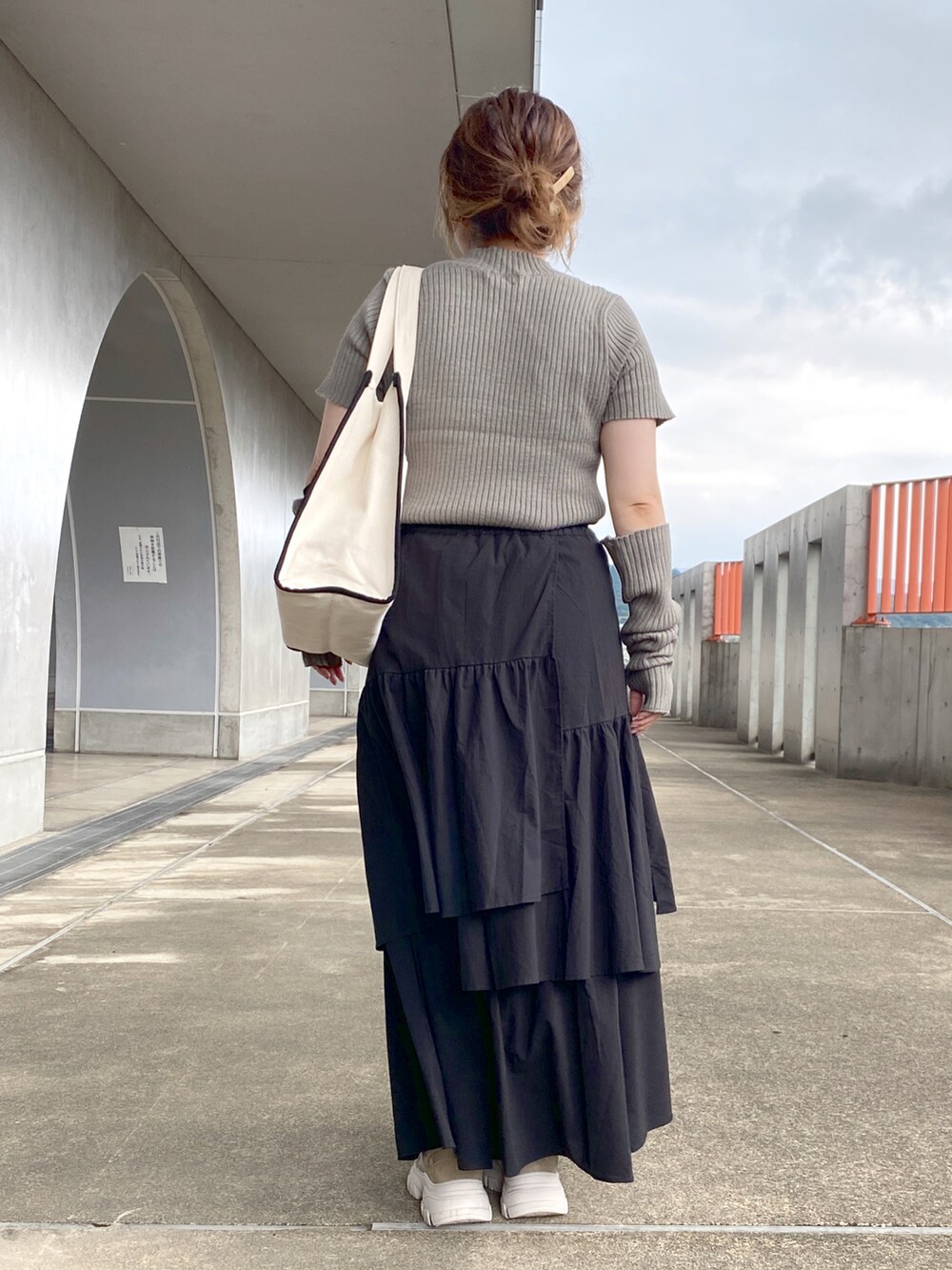 グリーン系のニット/セーター、ブラック系のトートバッグ、ブラック系のスカートを着用したレディースの夏コーディネートの3枚目の写真