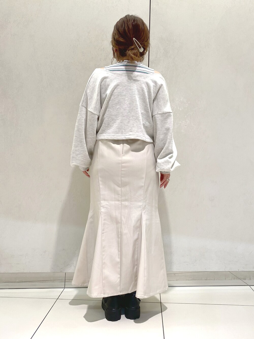 グレー系のカーディガン/ボレロ、ホワイト系のスカート、ブラック系のブーツを着用したレディースの春コーディネートの2枚目の写真