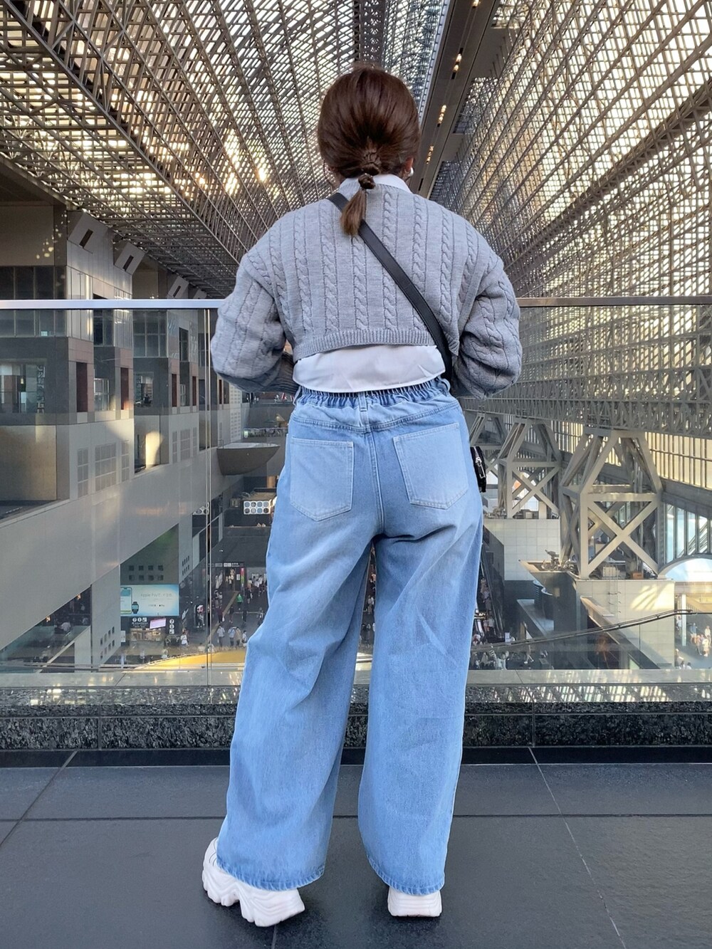 グレー系のニット/セーター、ブルー系のデニムパンツ、ブラック系のショルダーバッグを着用したレディースの夏コーディネートの4枚目の写真