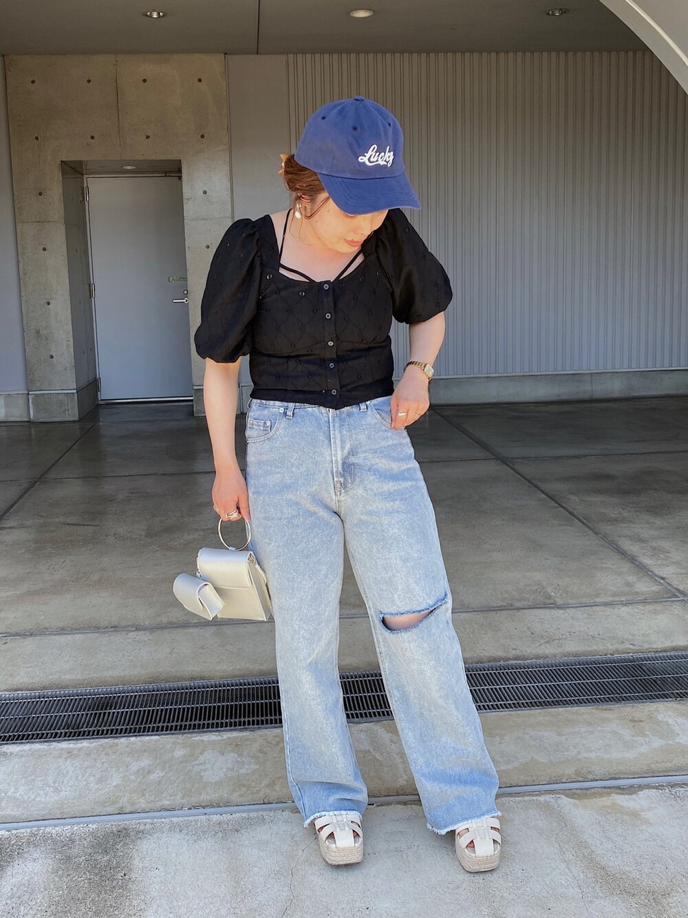 ブルー系のデニムパンツ、ホワイト系のサンダル、ブラック系のシャツ/ブラウスを着用したレディースの夏コーディネートの2枚目の写真