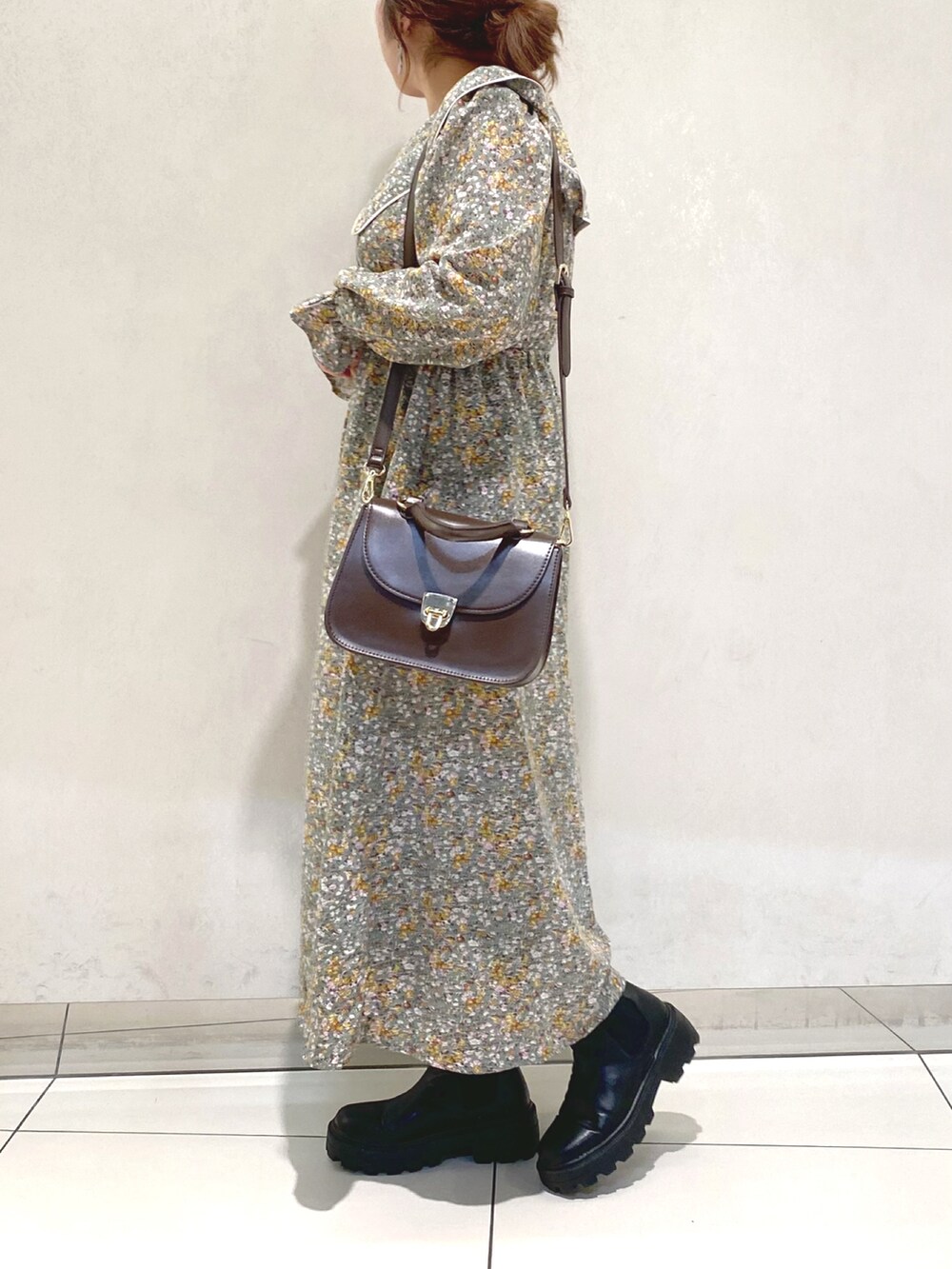 グリーン系のワンピース、ブラウン系のショルダーバッグ、ブラック系のブーツを着用したレディースの冬コーディネートの2枚目の写真