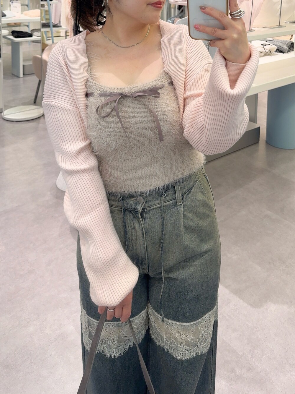 ピンク系のアンサンブル、ブルー系のデニムパンツ、ブラック系のショルダーバッグを着用したレディースの秋コーディネートの3枚目の写真