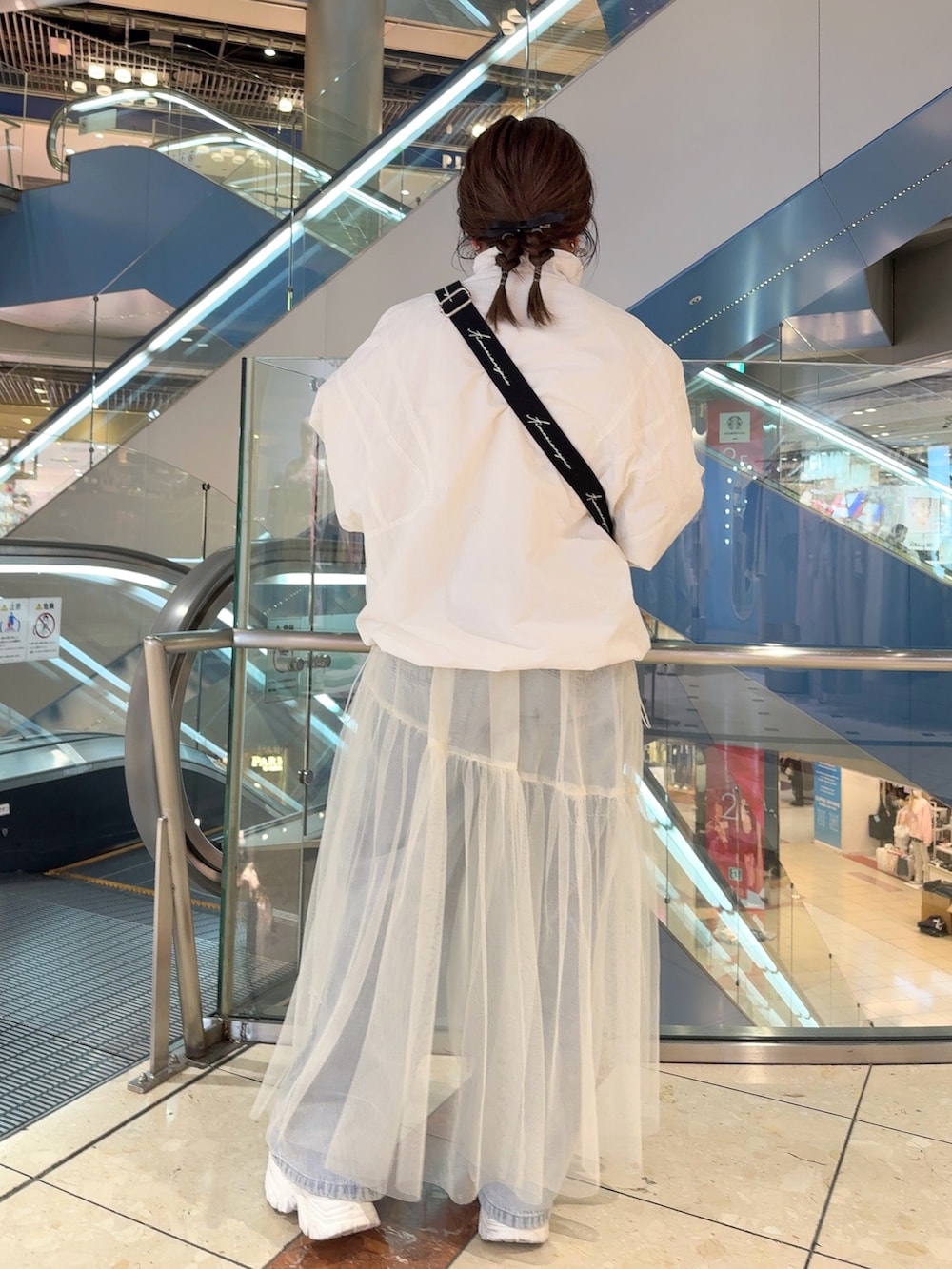 ホワイト系のマウンテンパーカー、ホワイト系のスカート、ホワイト系のショルダーバッグを着用したレディースの春コーディネートの3枚目の写真