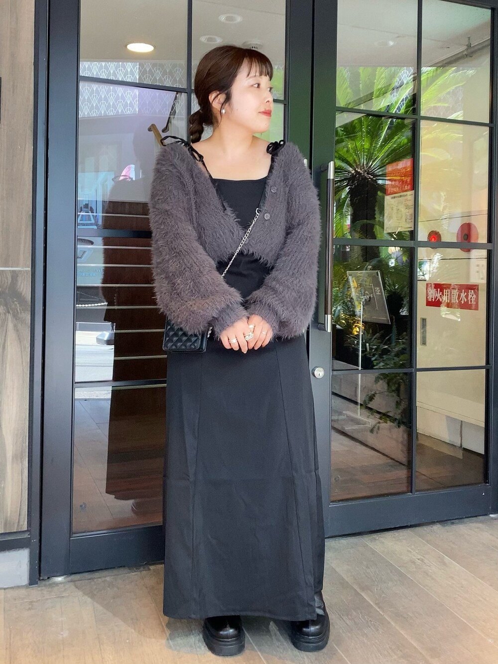 グレー系のワンピース、ブラック系のショルダーバッグ、ブラック系のブーツを着用したレディースの秋コーディネートの2枚目の写真