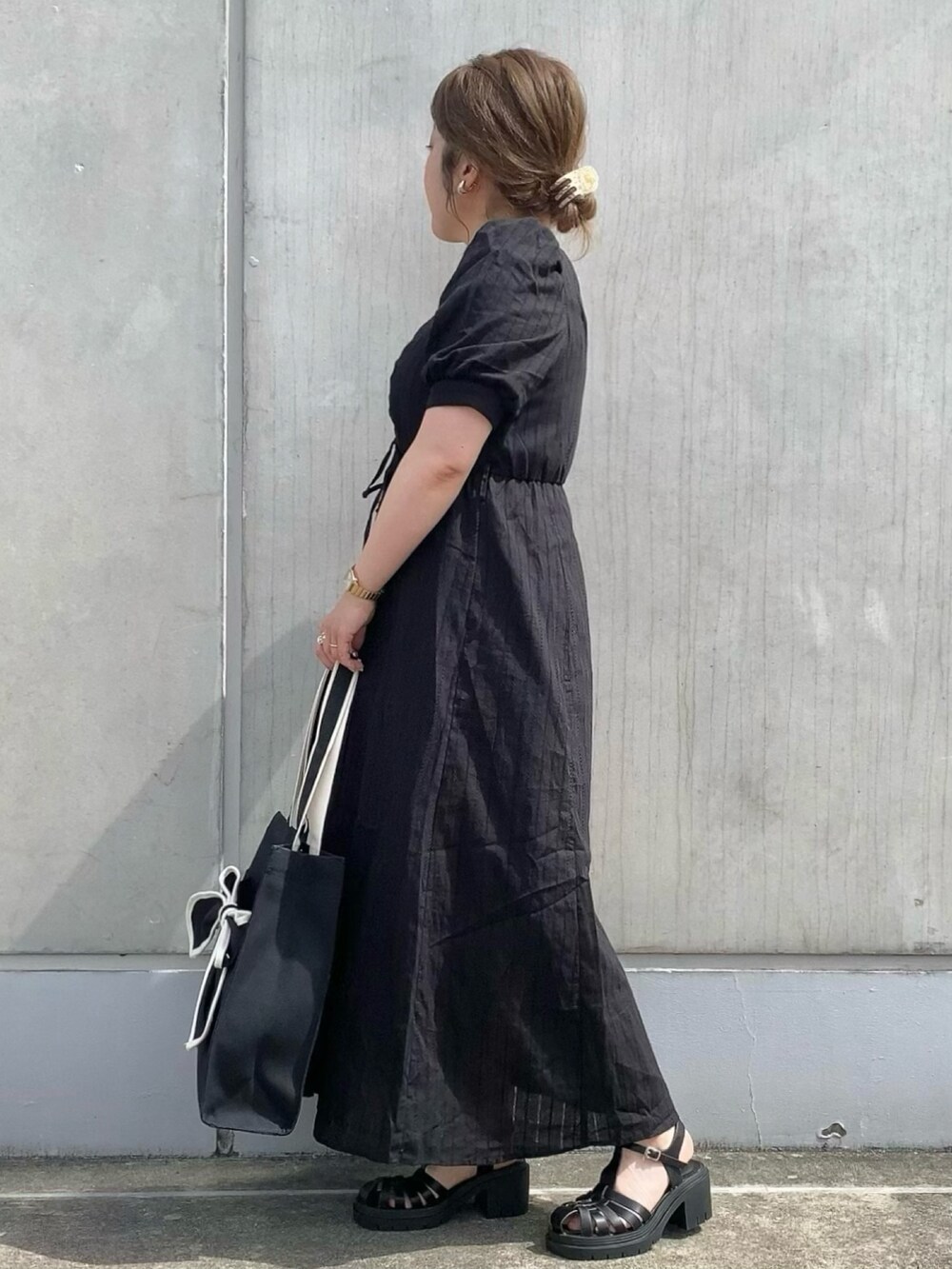 ブラック系のワンピース、ブラック系のトートバッグ、ブラック系のサンダルを着用したレディースの春コーディネートの3枚目の写真