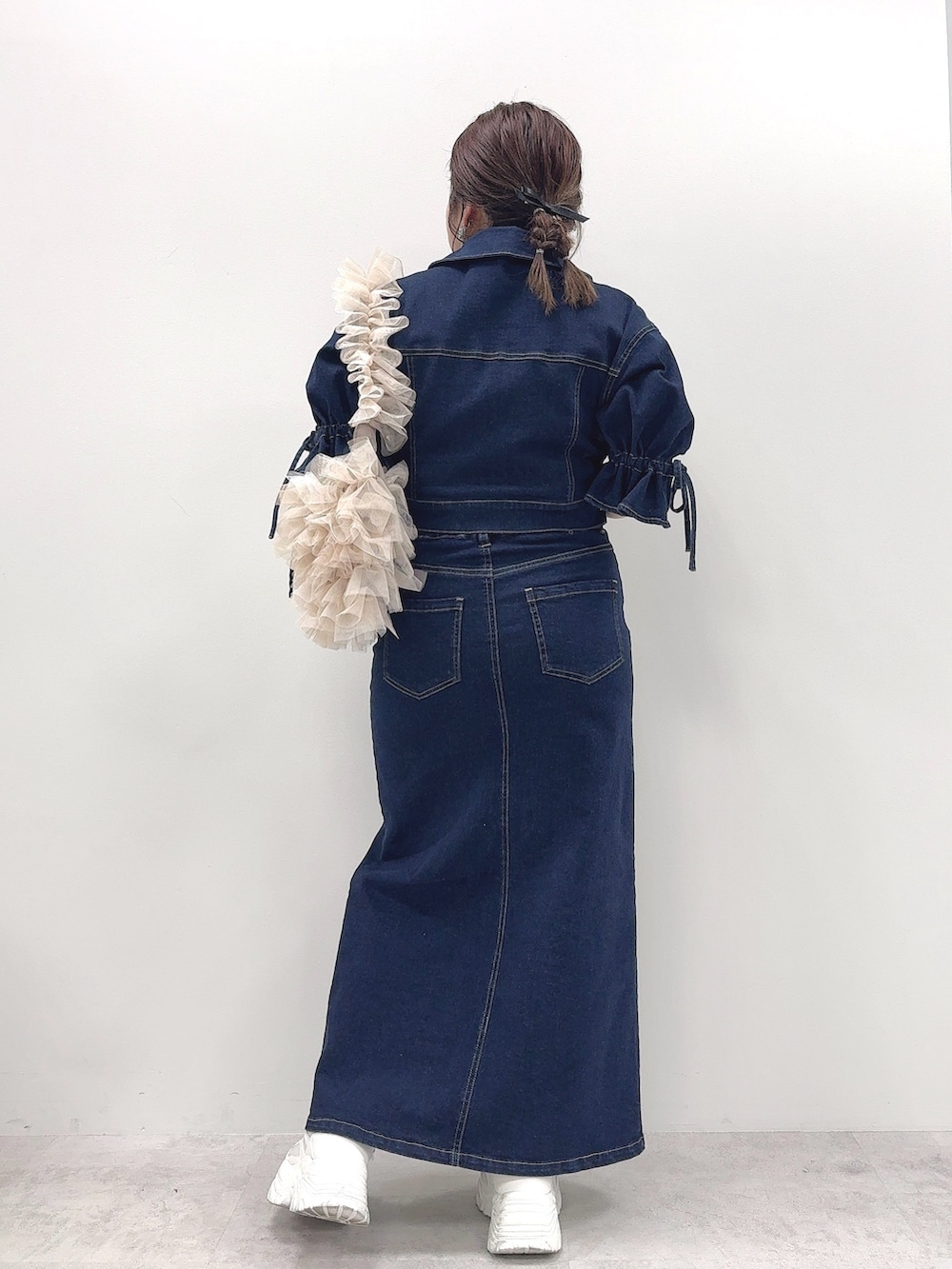 ブルー系のデニムジャケット、ブルー系のデニムスカート、ベージュ系のショルダーバッグを着用したレディースの春コーディネートの3枚目の写真