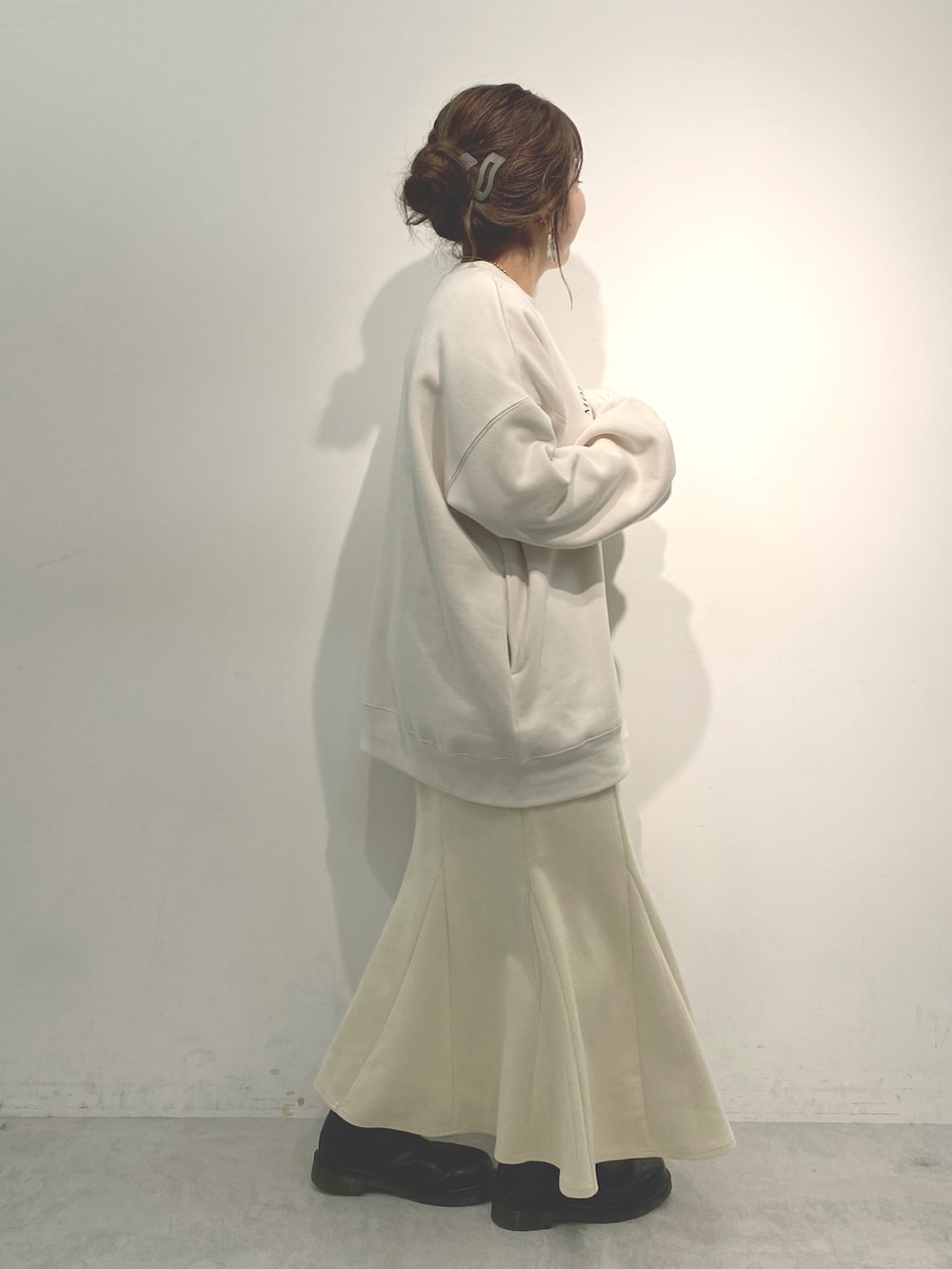 ホワイト系のスウェット、ホワイト系のスカート、ブラック系のブーツを着用したレディースの冬コーディネートの2枚目の写真