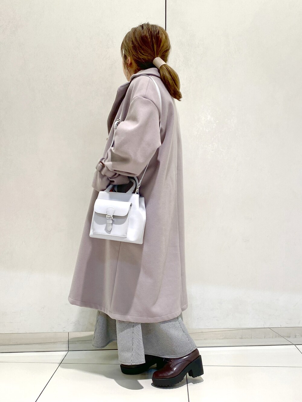 グレー系のベスト、ホワイト系のTシャツ/カットソー、ブラウン系のチェスターコートを着用したレディースの冬コーディネートの2枚目の写真