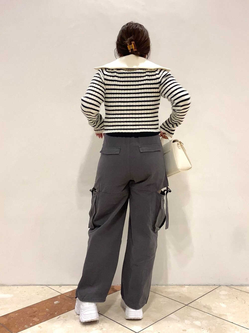 ブラック系のニット/セーター、グレー系のカーゴパンツ、ホワイト系のショルダーバッグを着用したレディースの秋コーディネートの4枚目の写真