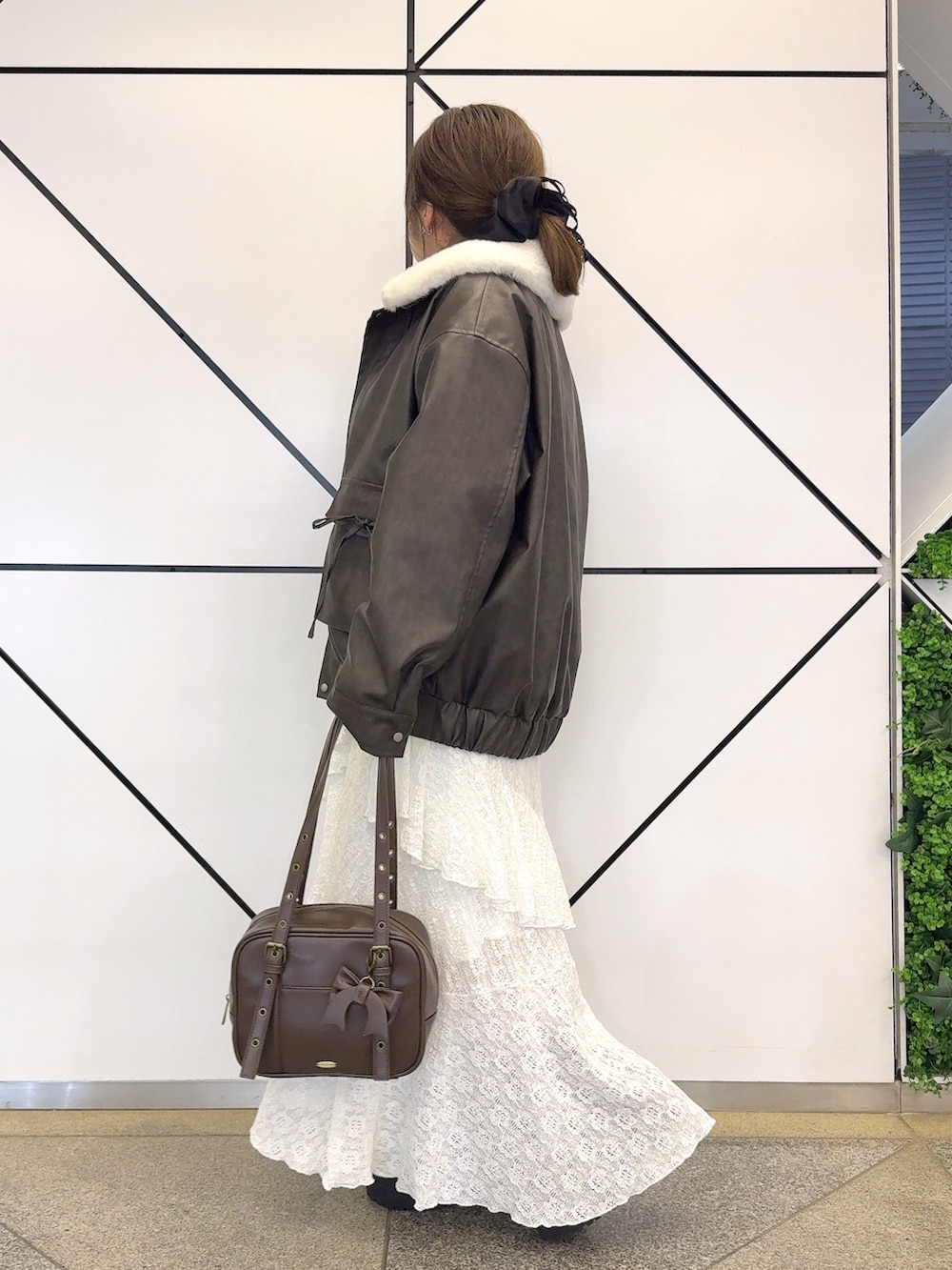 ブラック系のブルゾン、ホワイト系のワンピース、ブラウン系のショルダーバッグを着用したレディースの冬コーディネートの3枚目の写真