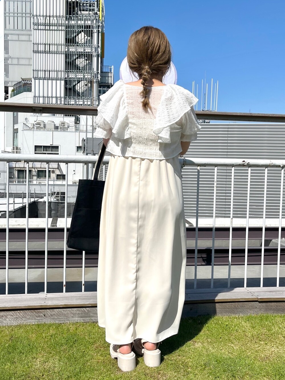 ホワイト系のワンピース、ブラック系のトートバッグ、ホワイト系のサンダルを着用したレディースの春コーディネートの3枚目の写真