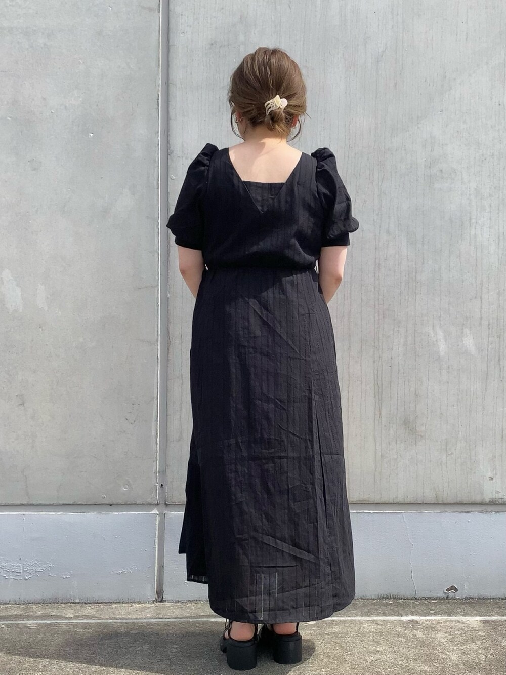 ブラック系のワンピース、ブラック系のトートバッグ、ブラック系のサンダルを着用したレディースの春コーディネートの4枚目の写真