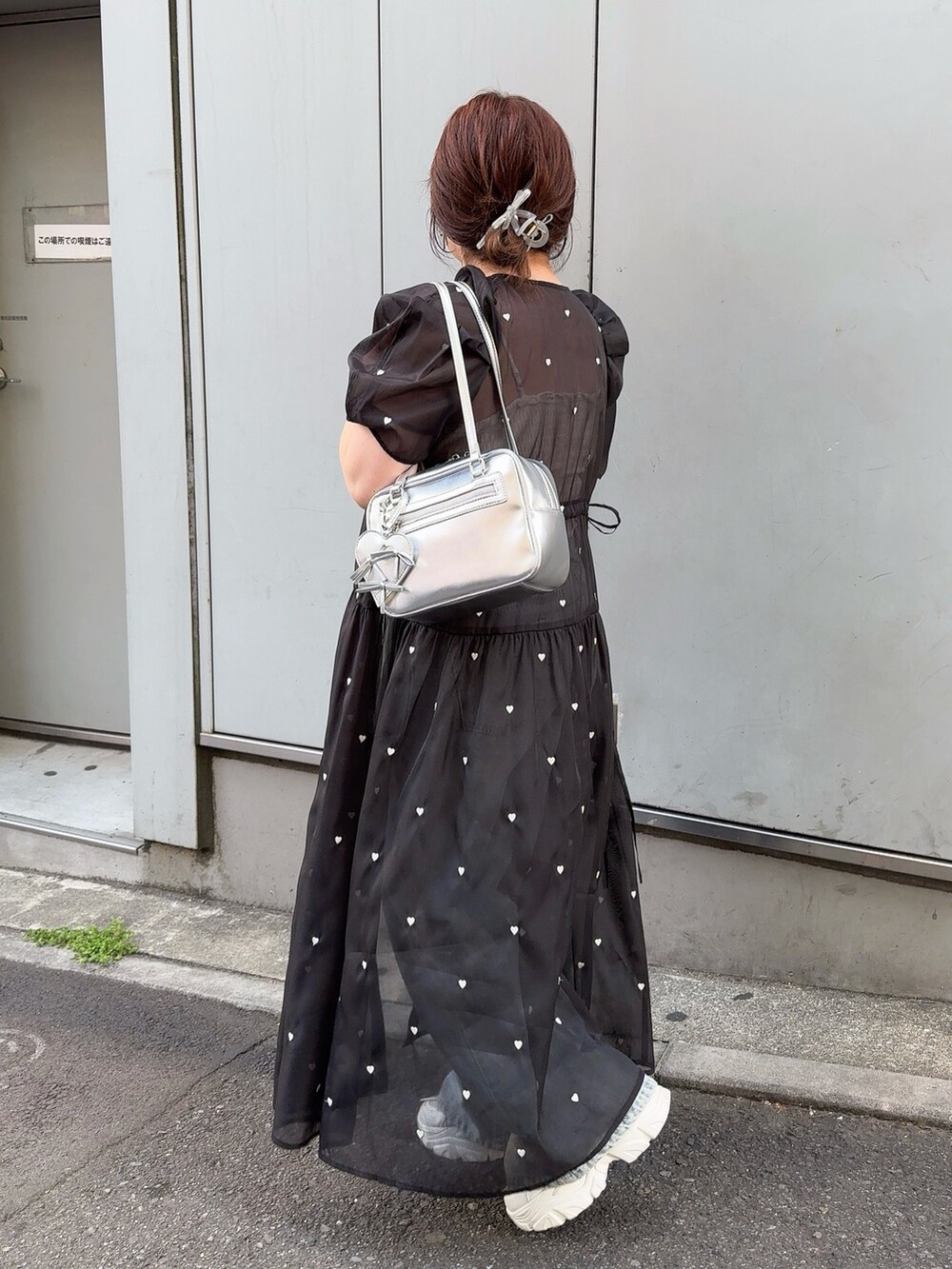 ブラック系のワンピース、ブルー系のデニムパンツ、ホワイト系のスニーカーを着用したレディースの春コーディネートの3枚目の写真