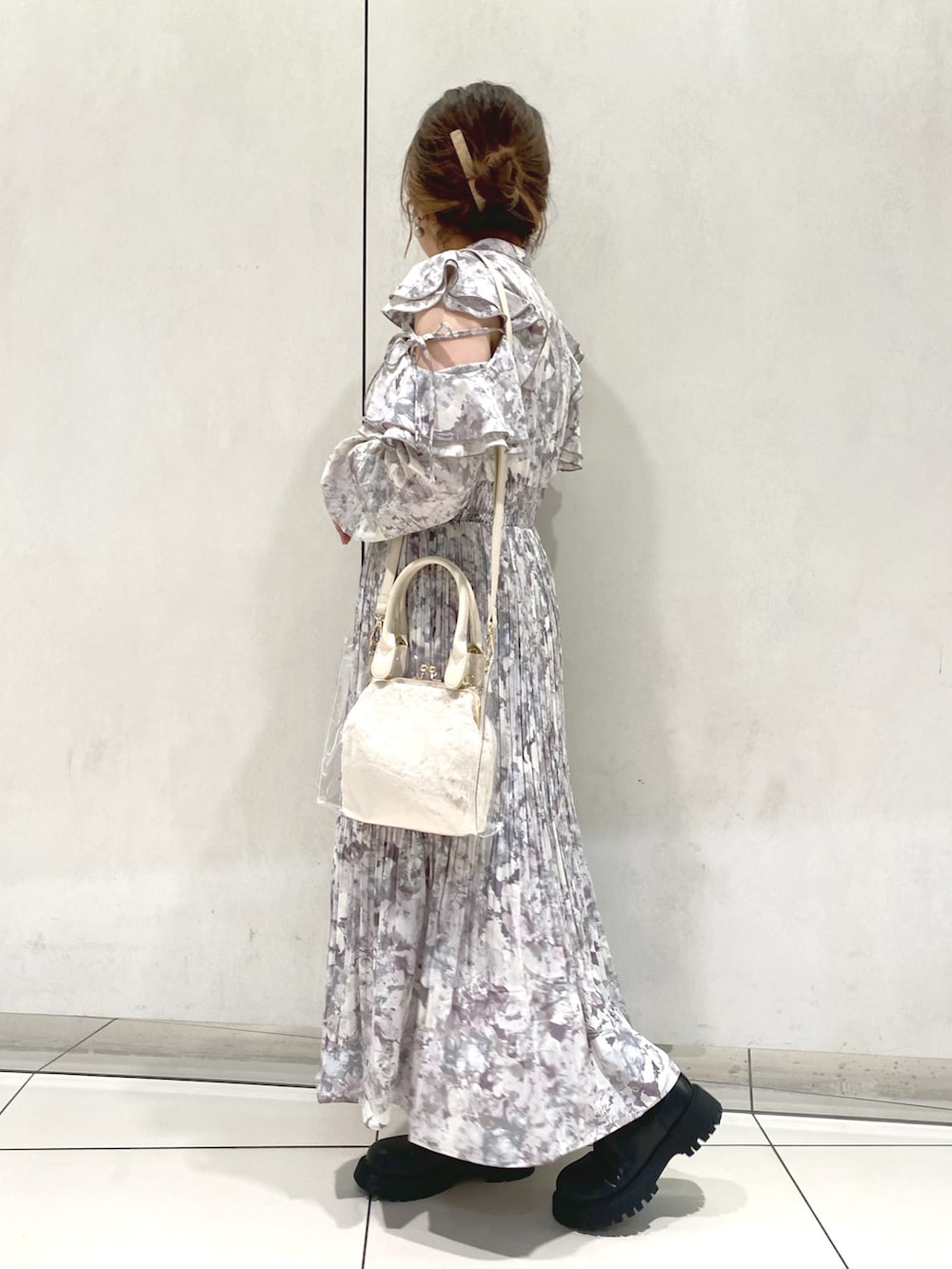 パープル系のワンピース、ブラック系のブーツ、ホワイト系のショルダーバッグを着用したレディースの秋コーディネートの2枚目の写真