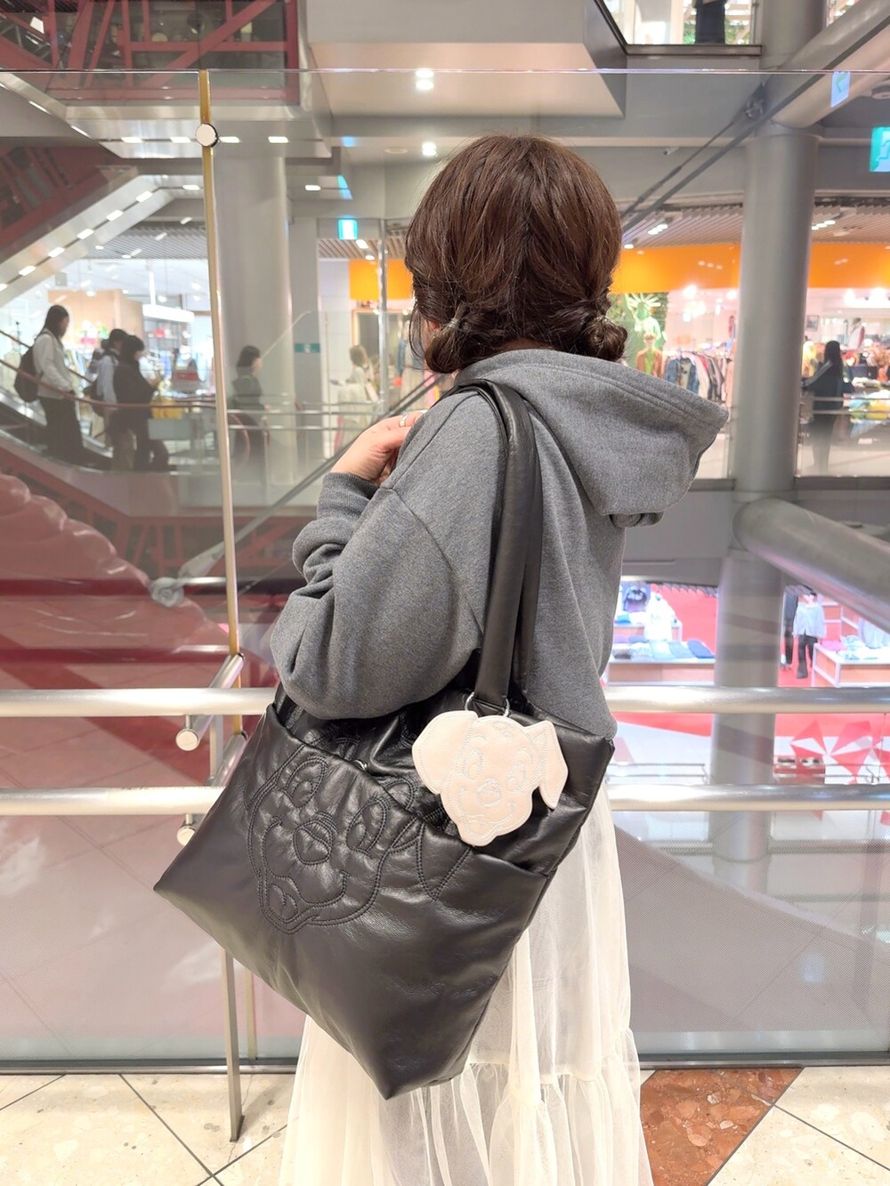 グレー系のパーカー、ホワイト系のスカート、ブラック系のトートバッグを着用したレディースの冬コーディネートの2枚目の写真