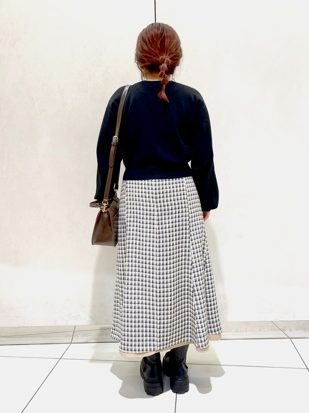 ベージュ系のスカート、ブラック系のブーツ、ブラウン系のショルダーバッグを着用したレディースの冬コーディネートの3枚目の写真