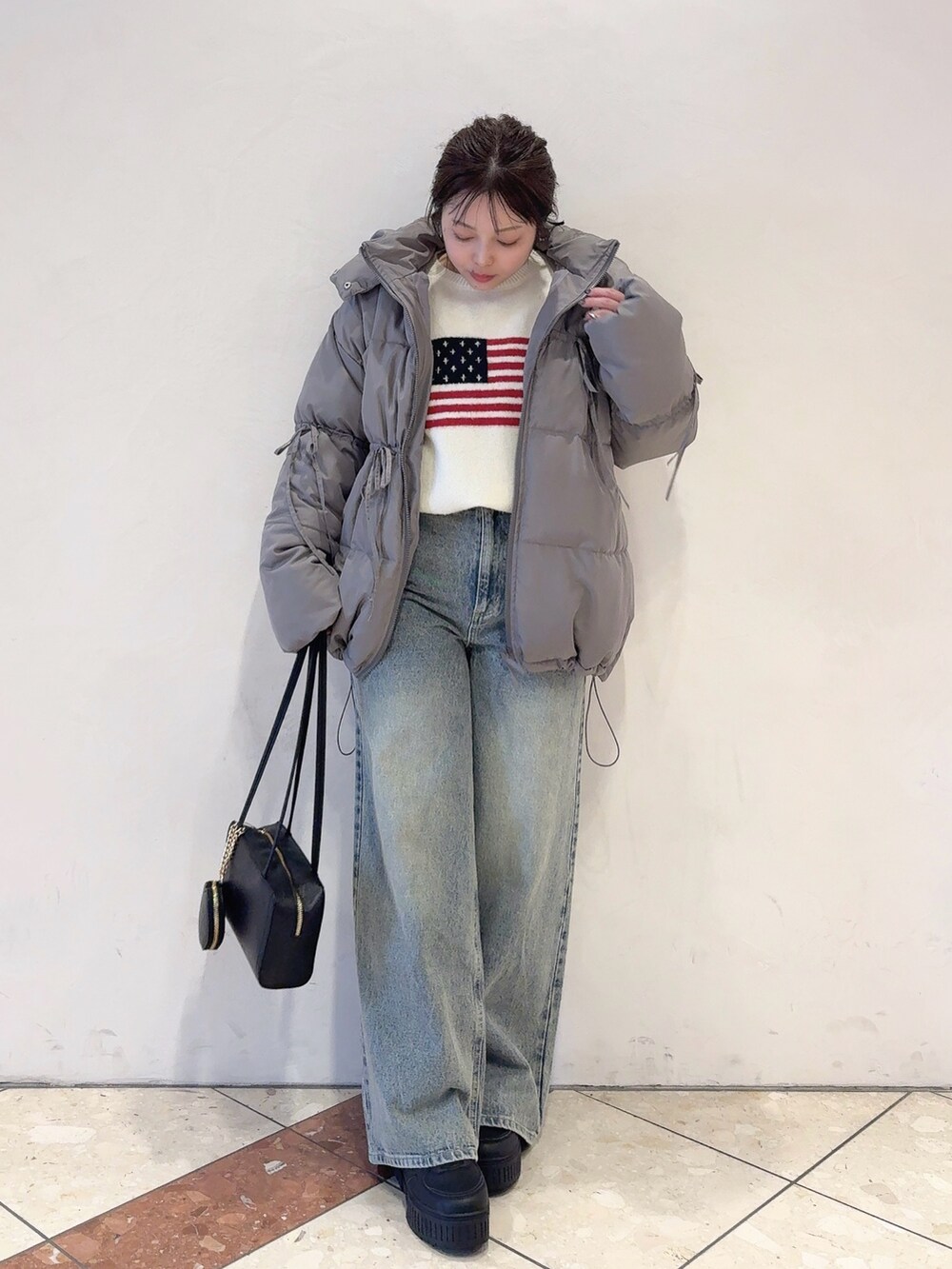 グレー系のダウンジャケット/コート、ホワイト系のニット/セーター、ブルー系のデニムパンツを着用したレディースの秋コーディネートの2枚目の写真