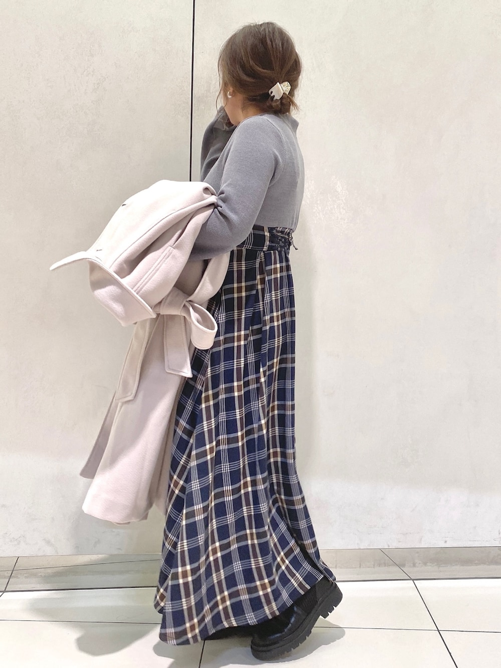 グレー系のワンピース、ホワイト系のステンカラーコート、ブラック系のブーツを着用したレディースの冬コーディネートの2枚目の写真