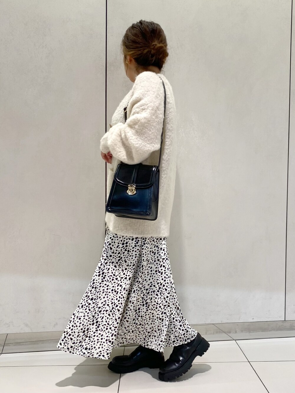 ホワイト系のカーディガン/ボレロ、ホワイト系のスカート、ブラック系のブーツを着用したレディースの秋コーディネートの2枚目の写真