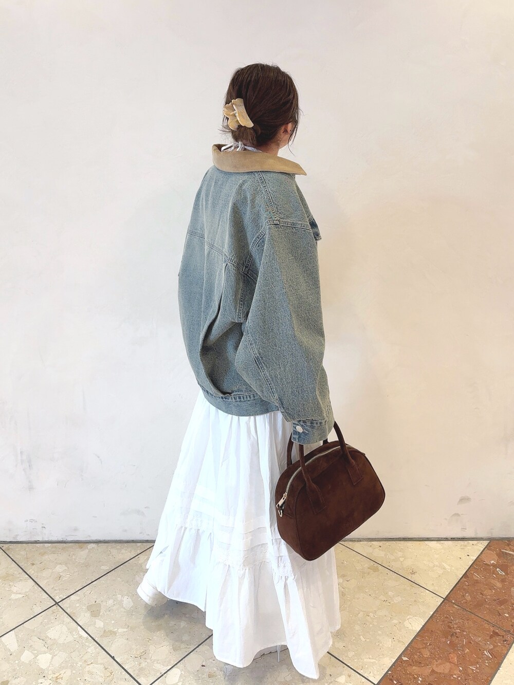 ブルー系のデニムジャケット、ホワイト系のTシャツ/カットソー、ブラウン系のショルダーバッグを着用したレディースの冬コーディネートの3枚目の写真