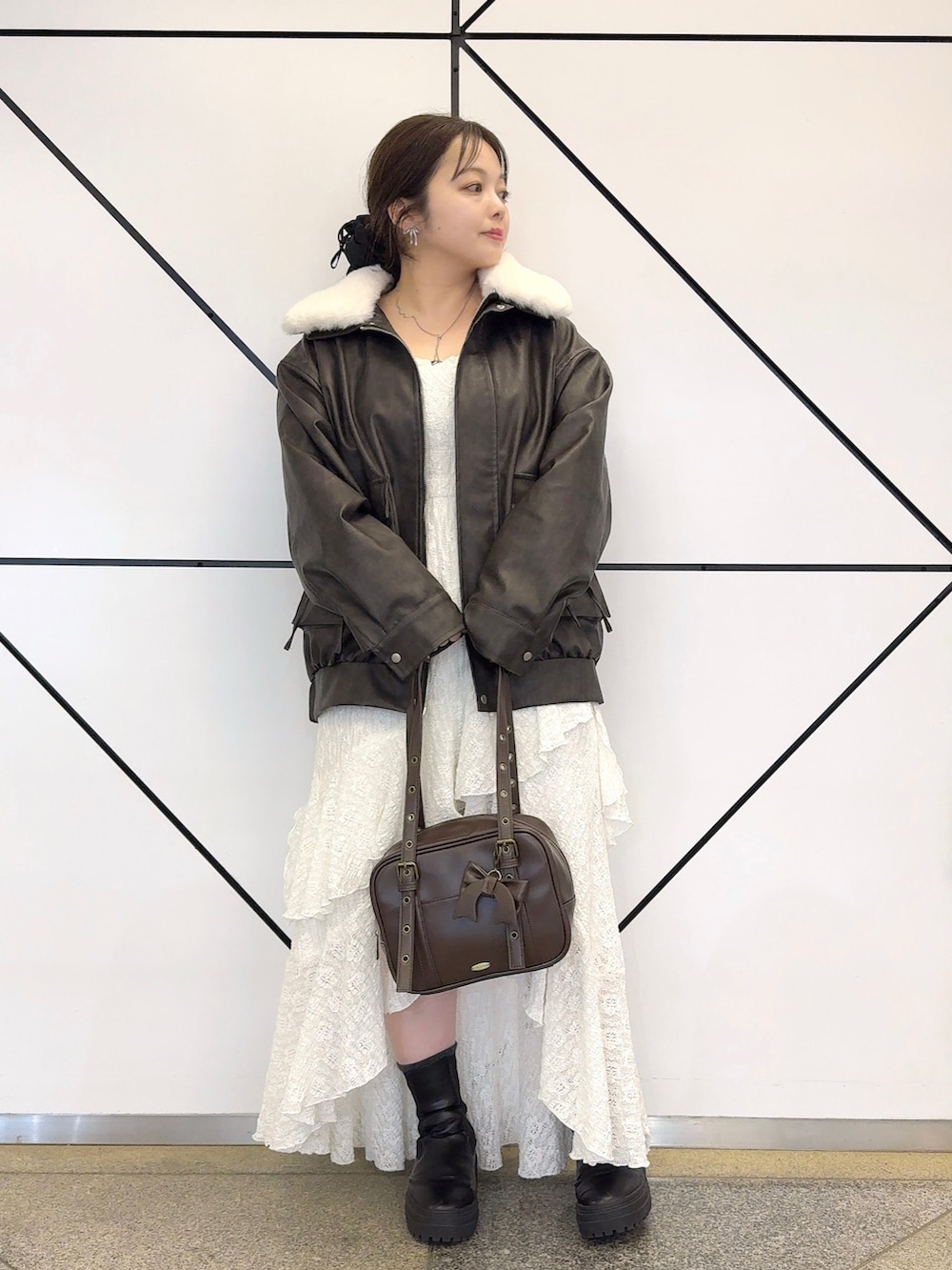 ブラック系のブルゾン、ホワイト系のワンピース、ブラウン系のショルダーバッグを着用したレディースの冬コーディネートの2枚目の写真