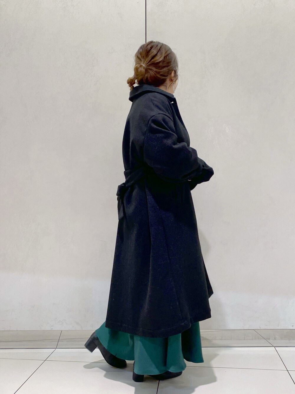 グレー系のニット/セーター、グリーン系のスカート、ブラック系のステンカラーコートを着用したレディースの秋コーディネートの2枚目の写真