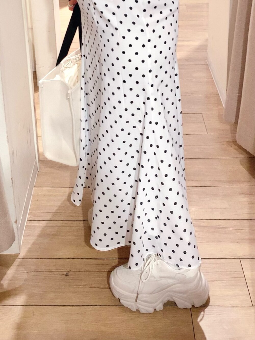 ブラック系のTシャツ/カットソー、ホワイト系のスカート、ブラック系のトートバッグを着用したレディースの春コーディネートの3枚目の写真