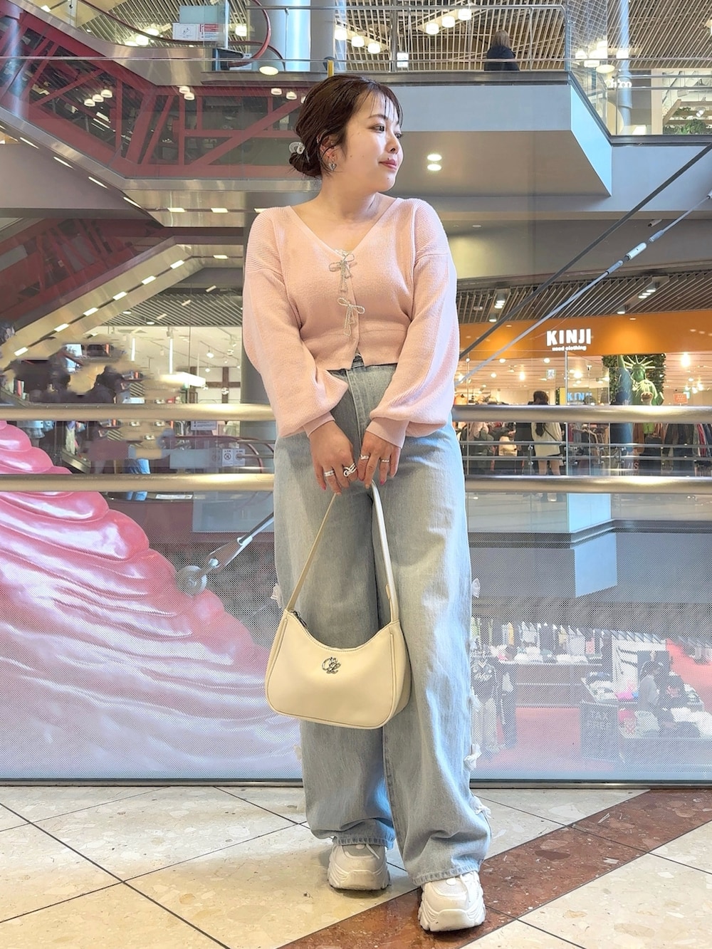 ピンク系のカーディガン/ボレロ、ブルー系のデニムパンツ、ホワイト系のショルダーバッグを着用したレディースの冬コーディネートの2枚目の写真