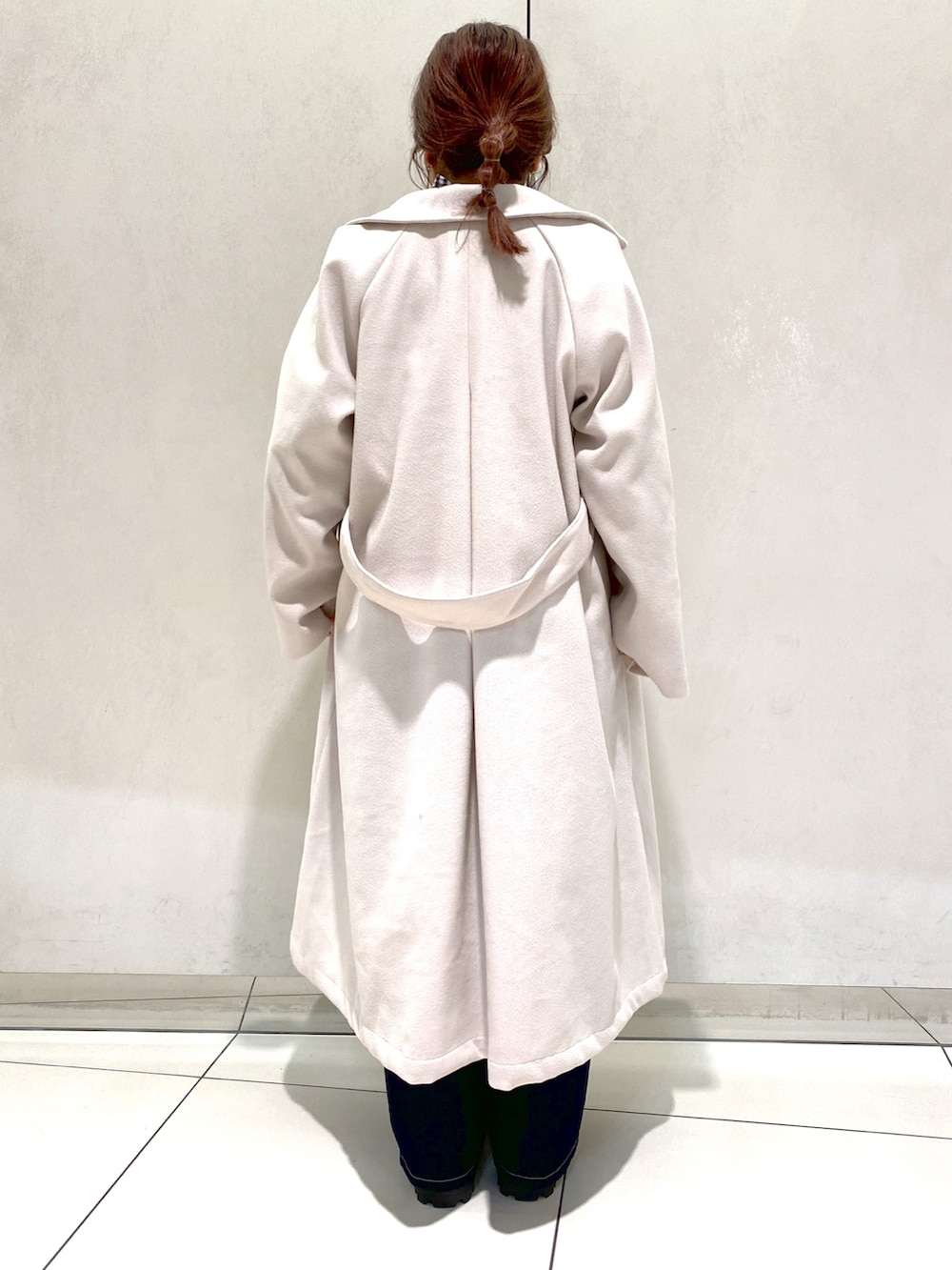 ホワイト系のステンカラーコート、ブラック系のシャツ/ブラウス、ブラック系のブーツを着用したレディースの冬コーディネートの3枚目の写真