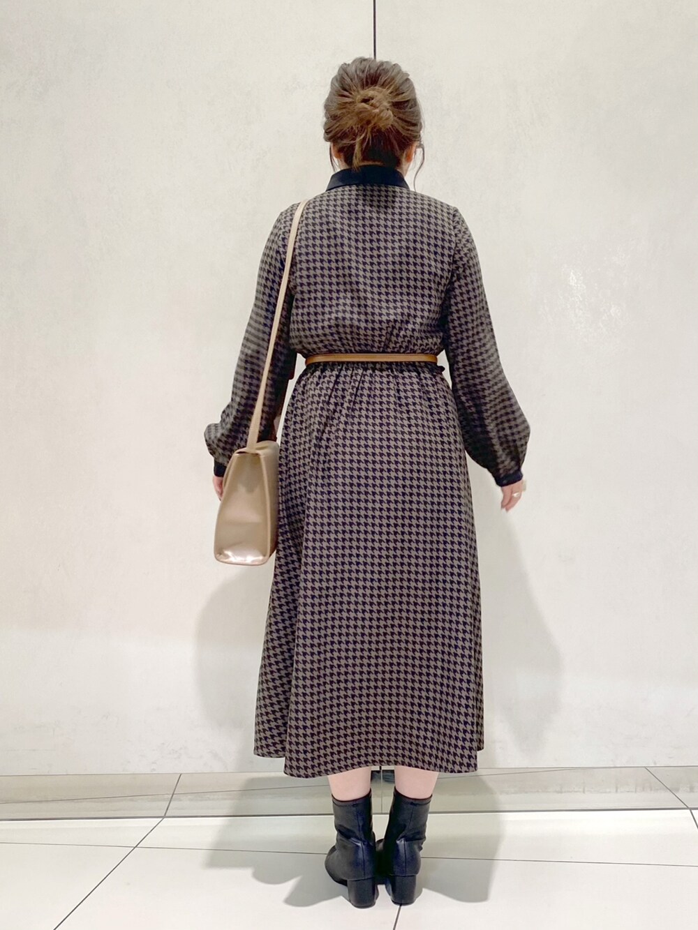 ブラウン系のワンピース、ベージュ系のショルダーバッグ、ブラック系のブーツを着用したレディースの冬コーディネートの3枚目の写真