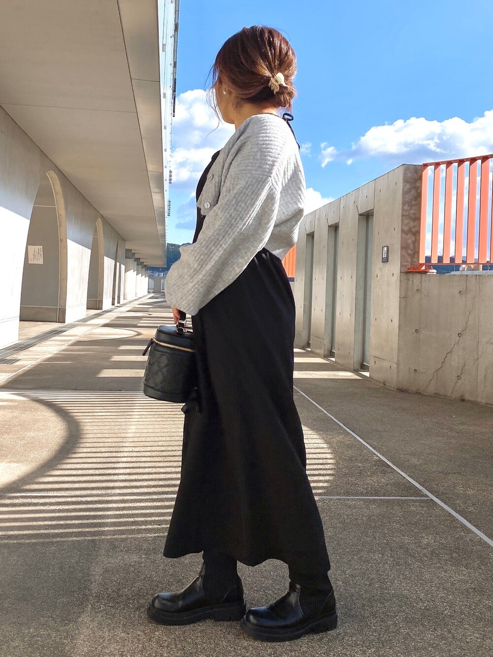 ブラック系のワンピース、ブラック系のショルダーバッグ、ブラック系のブーツを着用したレディースの冬コーディネートの3枚目の写真