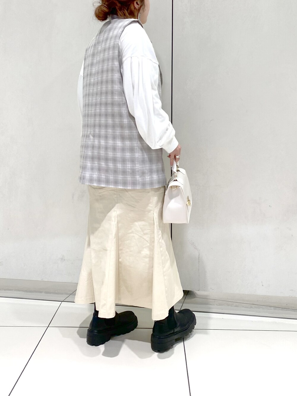 ホワイト系のスカート、ブラック系のブーツ、ホワイト系のショルダーバッグを着用したレディースの冬コーディネートの3枚目の写真