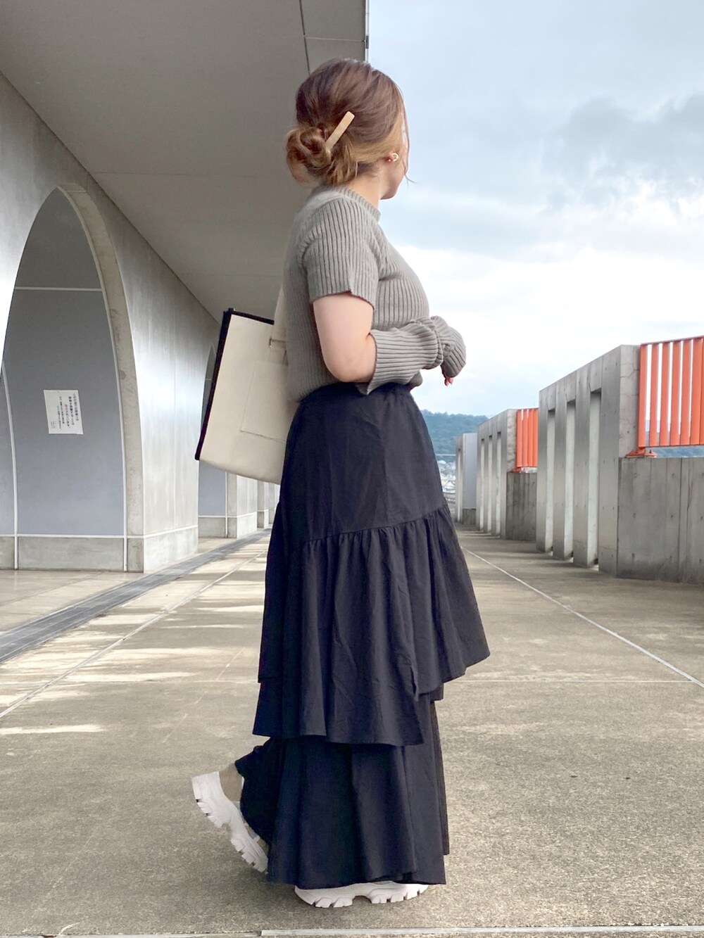 グリーン系のニット/セーター、ブラック系のトートバッグ、ブラック系のスカートを着用したレディースの夏コーディネートの4枚目の写真