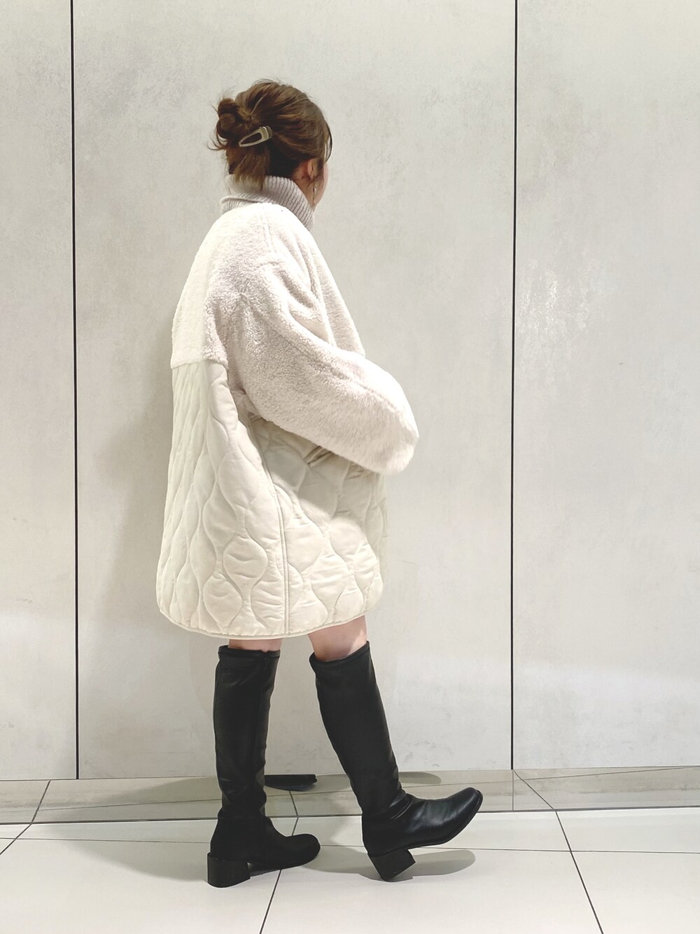 ホワイト系のノーカラーコート、グレー系のニット/セーター、ベージュ系のワンピースを着用したレディースの冬コーディネートの2枚目の写真