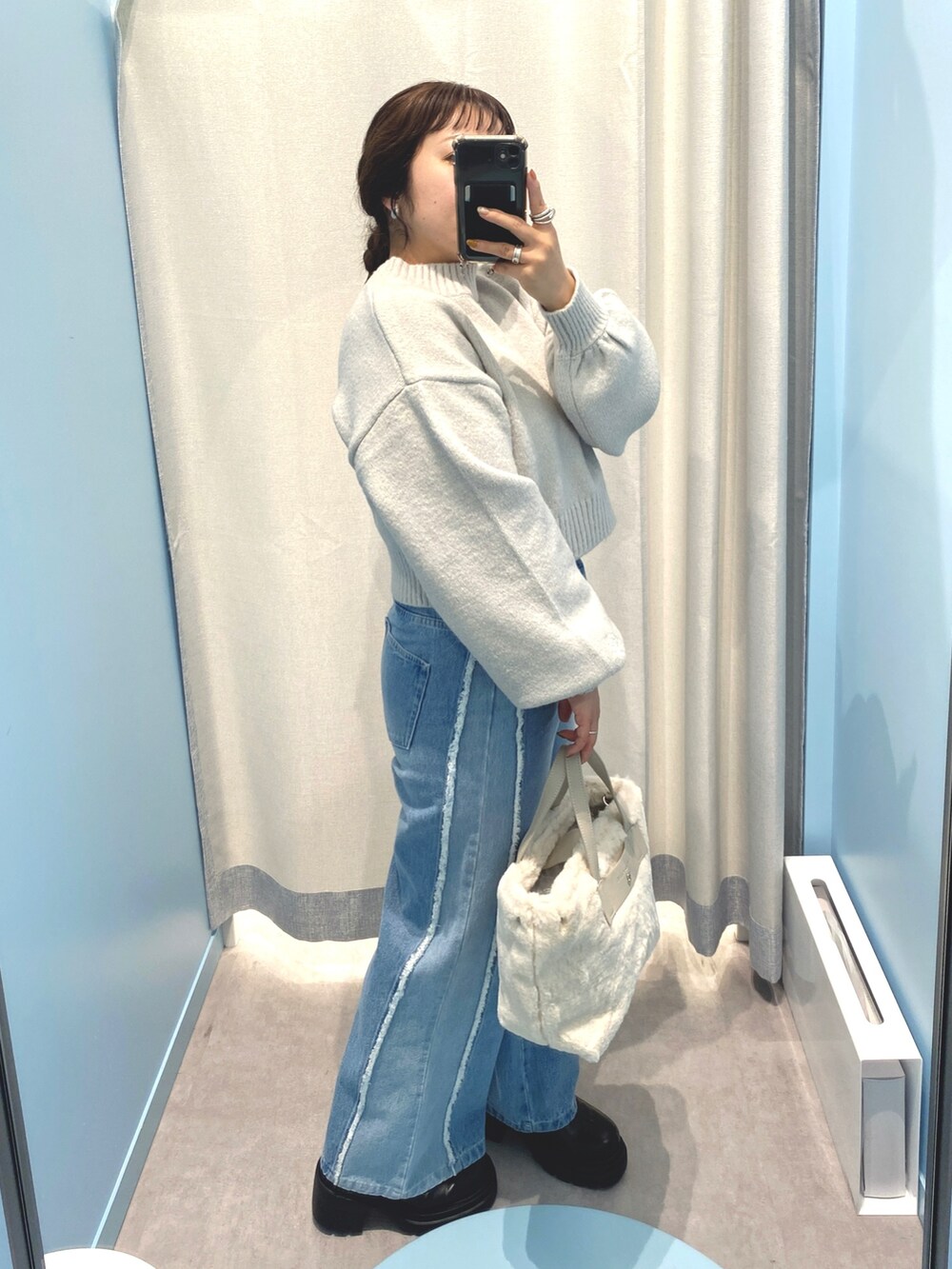 グレー系のニット/セーター、ブルー系のデニムパンツ、ホワイト系のショルダーバッグを着用したレディースの秋コーディネートの3枚目の写真