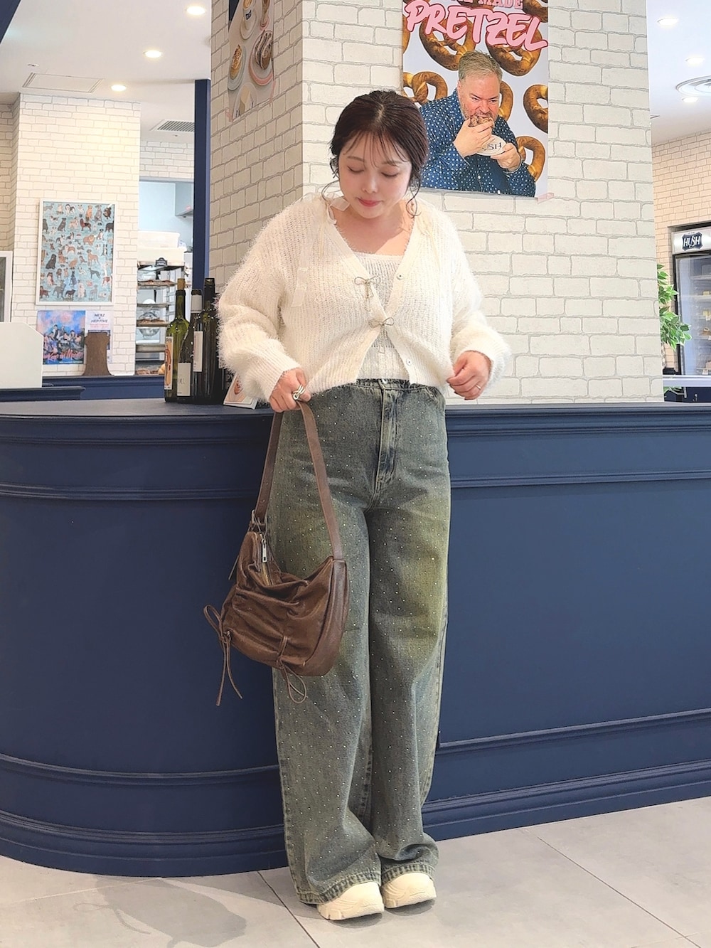 ホワイト系のカーディガン/ボレロ、ホワイト系のアンサンブル、ブルー系のデニムパンツを着用したレディースの秋コーディネートの2枚目の写真