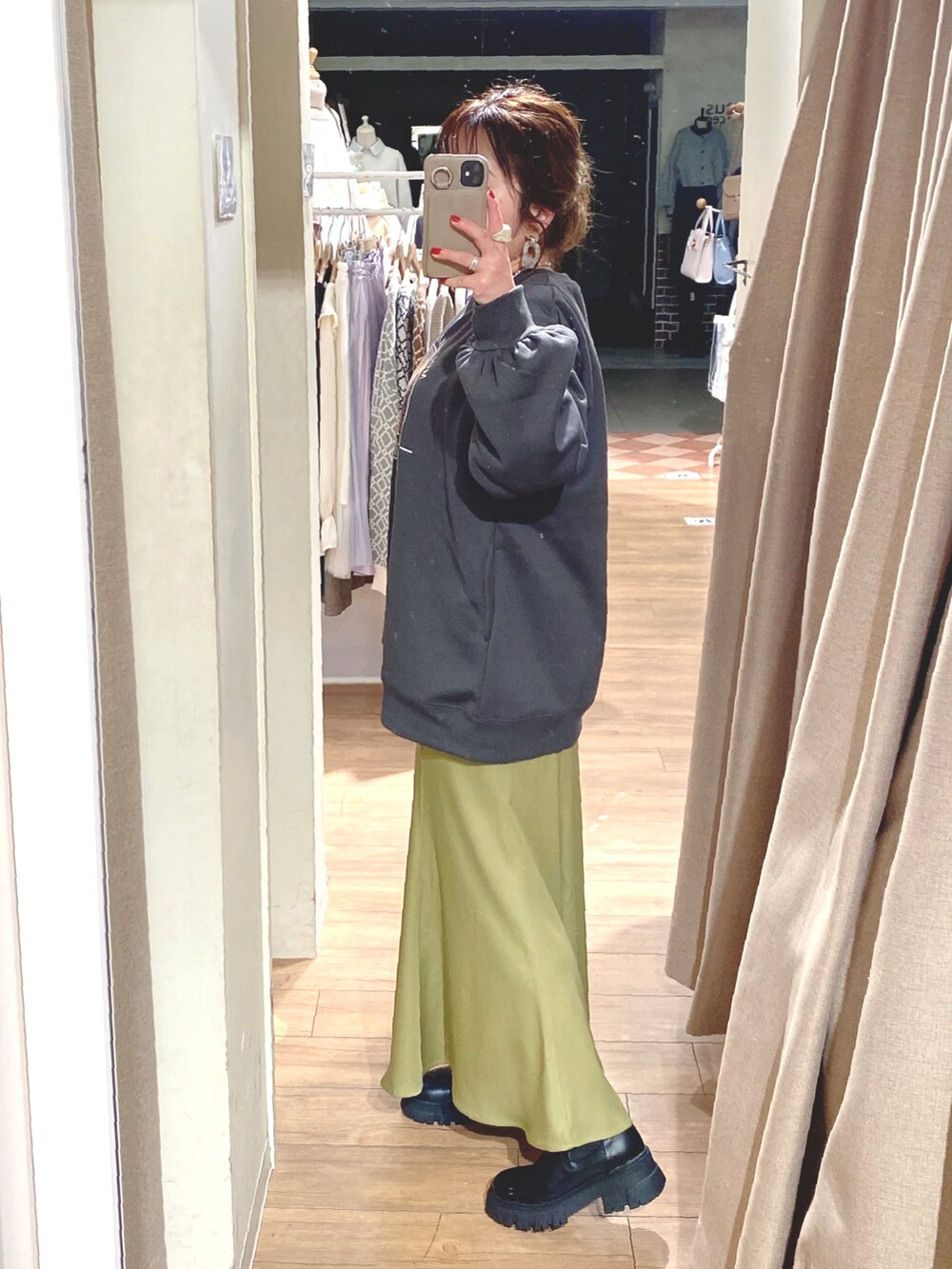 ブラック系のスウェット、グリーン系のスカート、ブラック系のブーツを着用したレディースの冬コーディネートの2枚目の写真