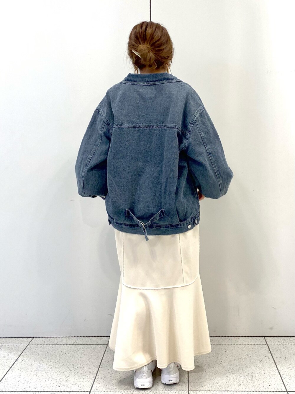ホワイト系のスカート、ホワイト系のスニーカー、ブルー系のデニムジャケットを着用したレディースの春コーディネートの3枚目の写真