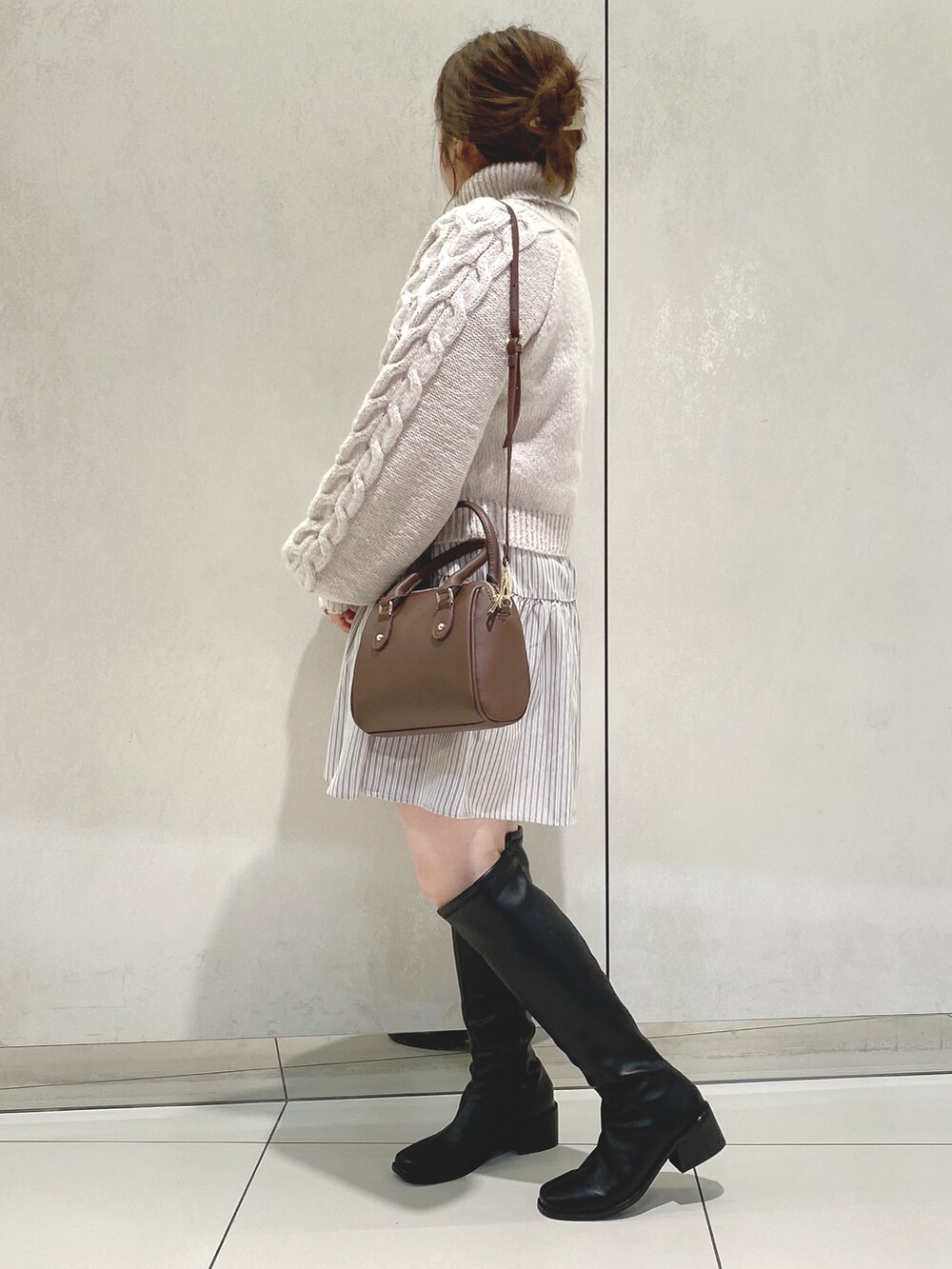 グレー系のニット/セーター、ベージュ系のワンピース、ブラック系のブーツを着用したレディースの冬コーディネートの2枚目の写真