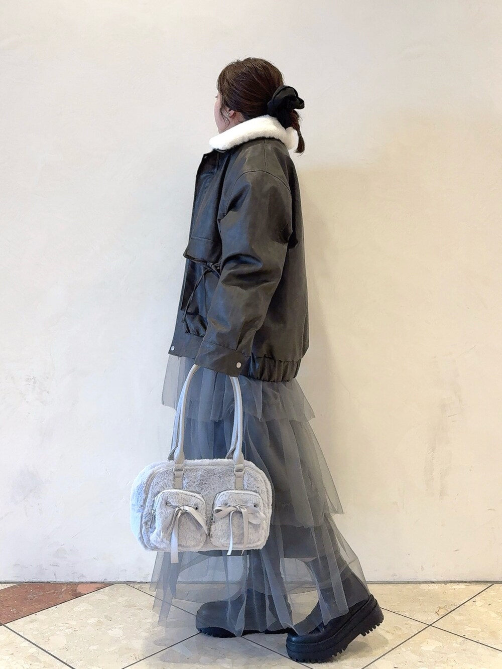 ブラック系のブルゾン、グレー系のワンピース、ブルー系のショルダーバッグを着用したレディースの冬コーディネートの3枚目の写真