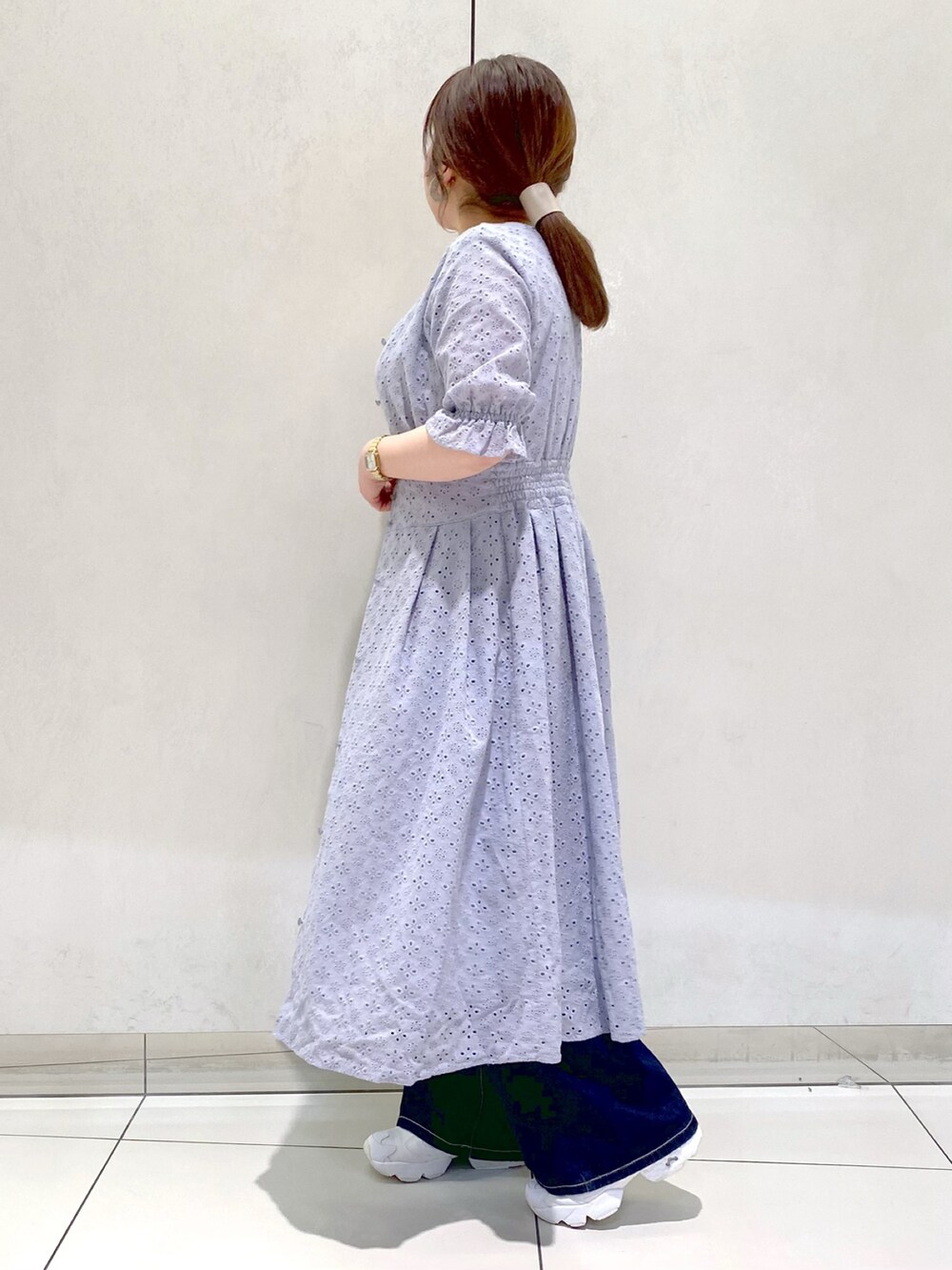 ブルー系のデニムパンツ、ホワイト系のスニーカー、ブルー系のワンピースを着用したレディースの春コーディネートの3枚目の写真