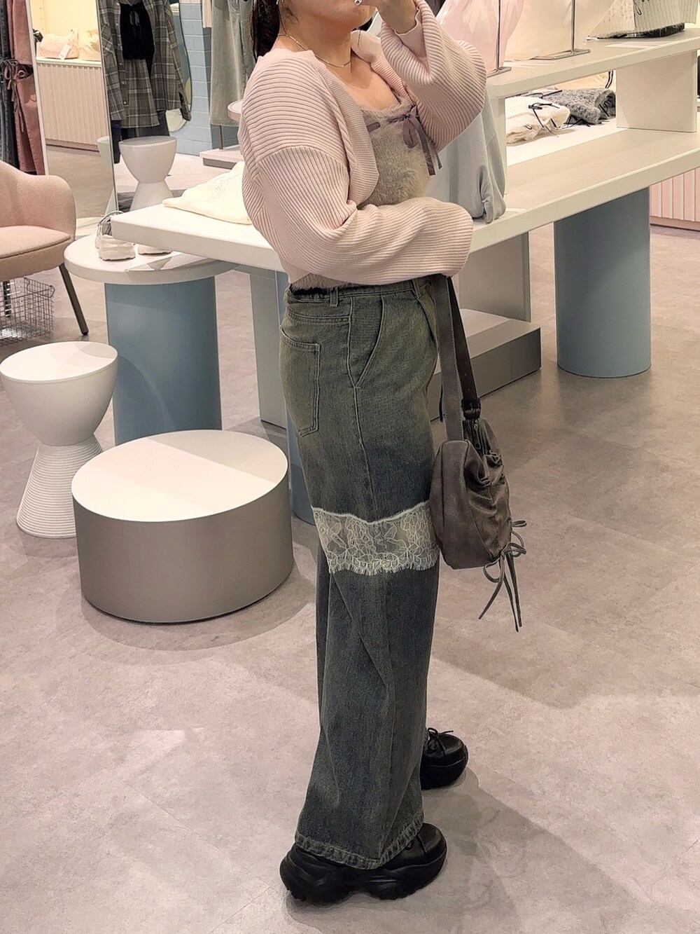 ピンク系のアンサンブル、ブルー系のデニムパンツ、ブラック系のショルダーバッグを着用したレディースの秋コーディネートの2枚目の写真