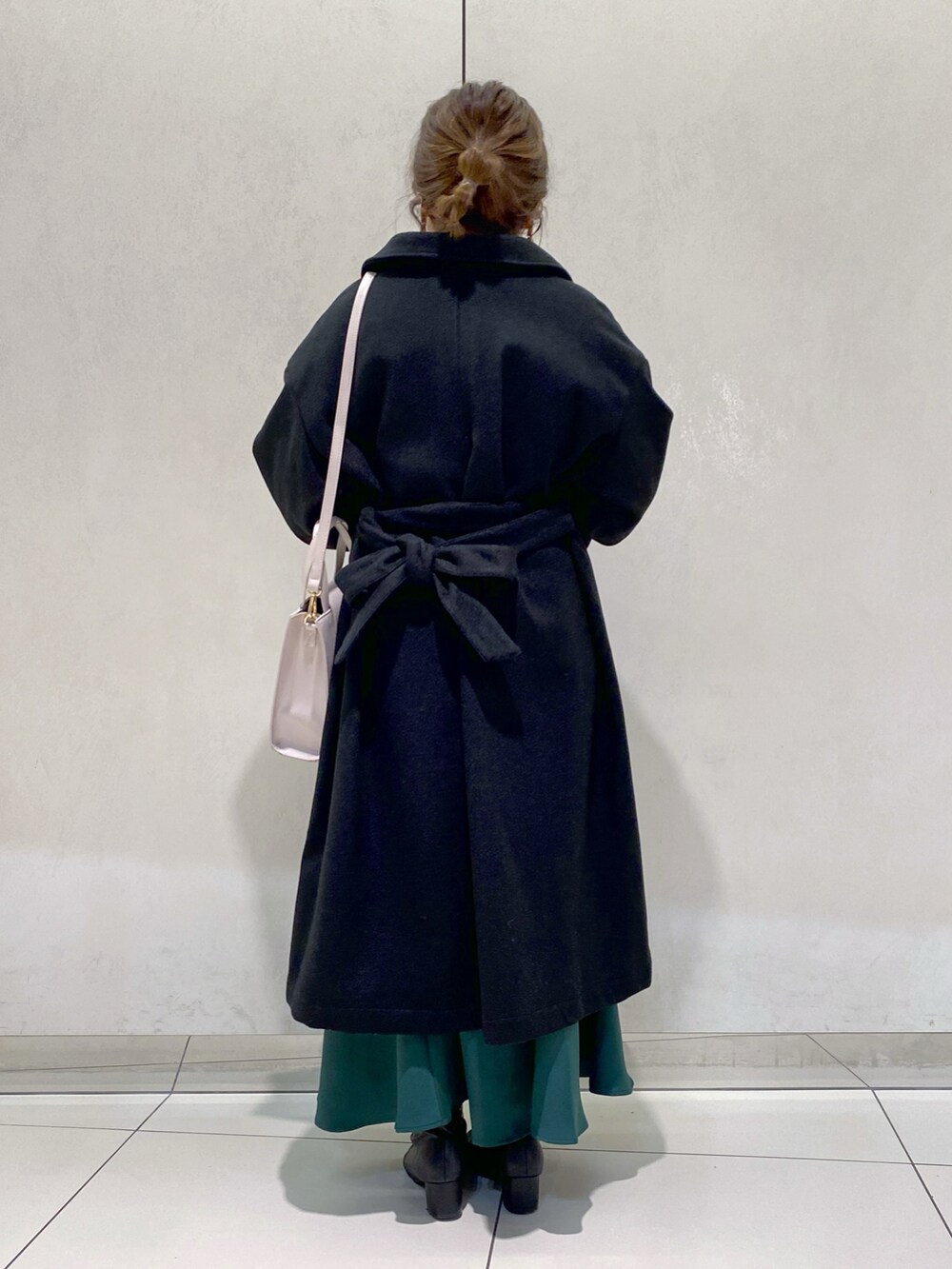 グレー系のニット/セーター、グリーン系のスカート、ブラック系のステンカラーコートを着用したレディースの秋コーディネートの3枚目の写真