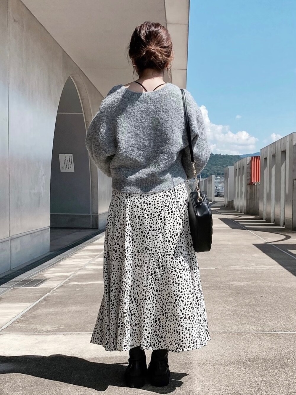 ホワイト系のスカート、ブラック系のブーツ、ブラック系のショルダーバッグを着用したレディースの秋コーディネートの3枚目の写真