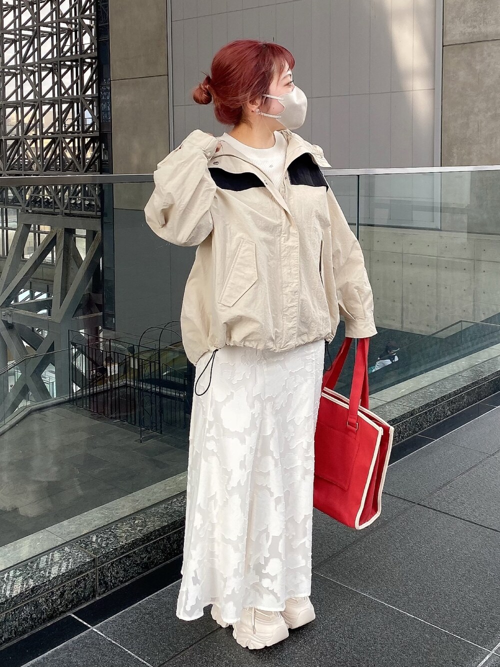 ホワイト系のスカート、ベージュ系のマウンテンパーカー、ホワイト系のニット/セーターを着用したレディースの春コーディネートの2枚目の写真